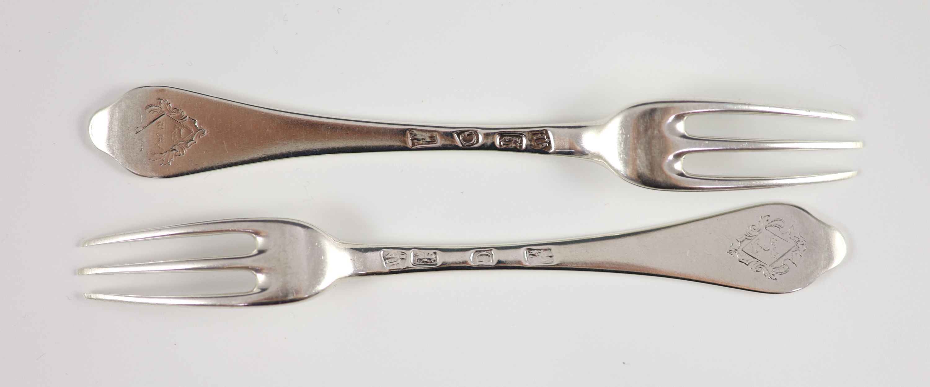 A pair of George I silver three-prong forks, with dog nose terminals, engraved with armorials, London 1722 by Paul Hanet, each 18 cm long, 4oz.